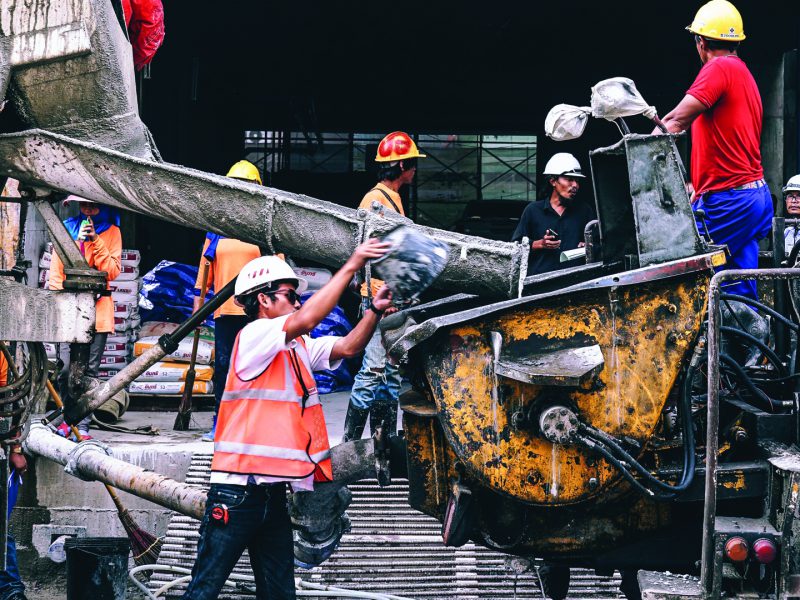 Contruction worker pouring wet concrete into construction equipment