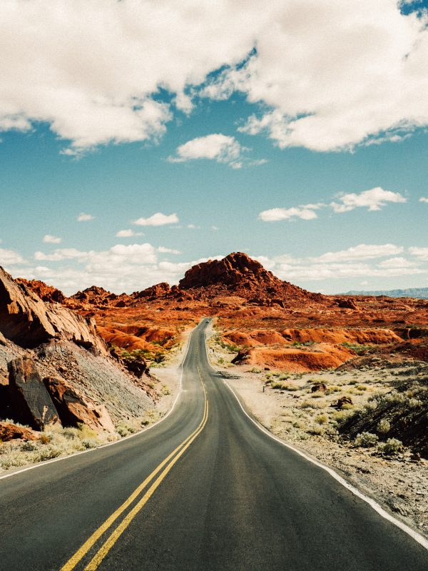 Difficult two-way road leading to beautiful orange-like desert mountain destination