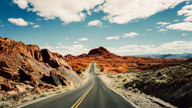 Difficult two-way road leading to beautiful orange-like desert mountain destination