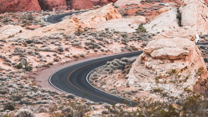 Difficult winding two-way road leading to beautiful orange-like desert mountain destination